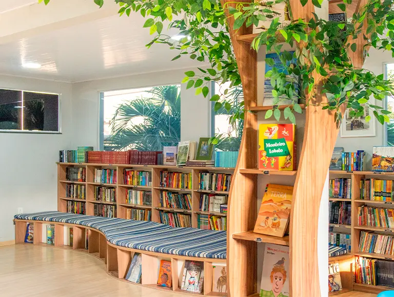 Biblioteca da EcoEscola Monteiro Lobato com estantes em formato de árvore
