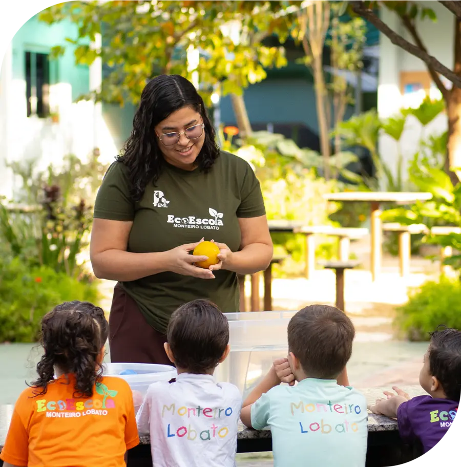 Educadora da EcoEscola Monteiro Lobato com alunos da Educação Infantil no pátio arborizado